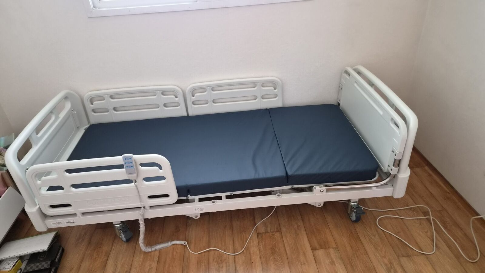 세종 재가복지와 함께 안내하는 복지용구 참고사진 - 흰 벽 방에 설치된 전동침대와 유선 리모컨