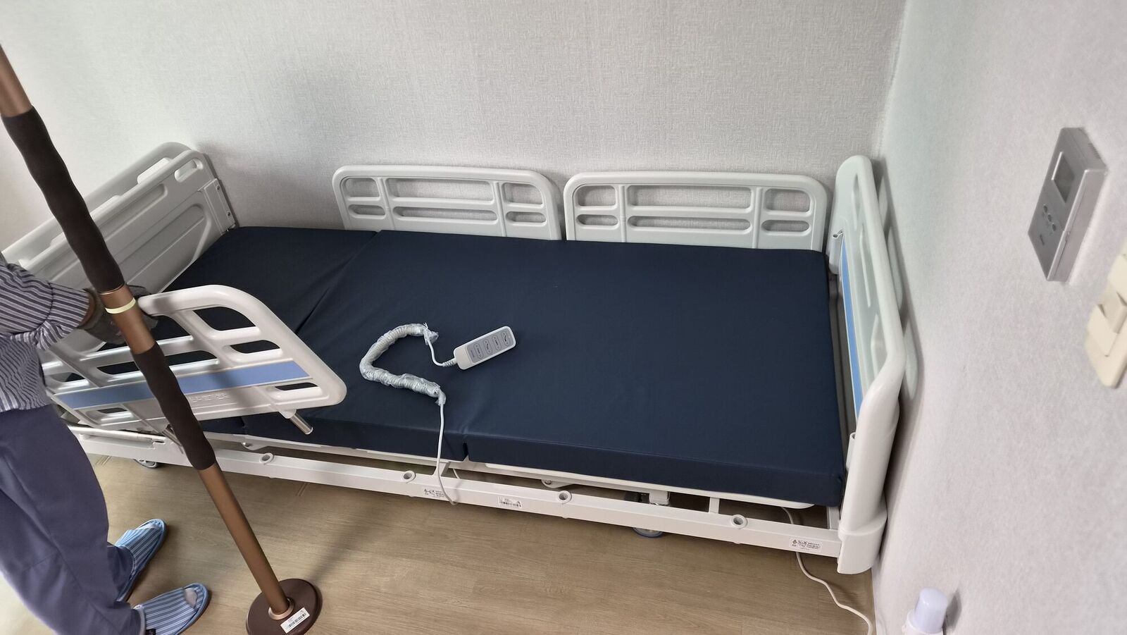 세종 재가복지와 함께 안내하는 복지용구 참고사진 - 보조 기둥 옆에 설치된 전동침대와 리모컨